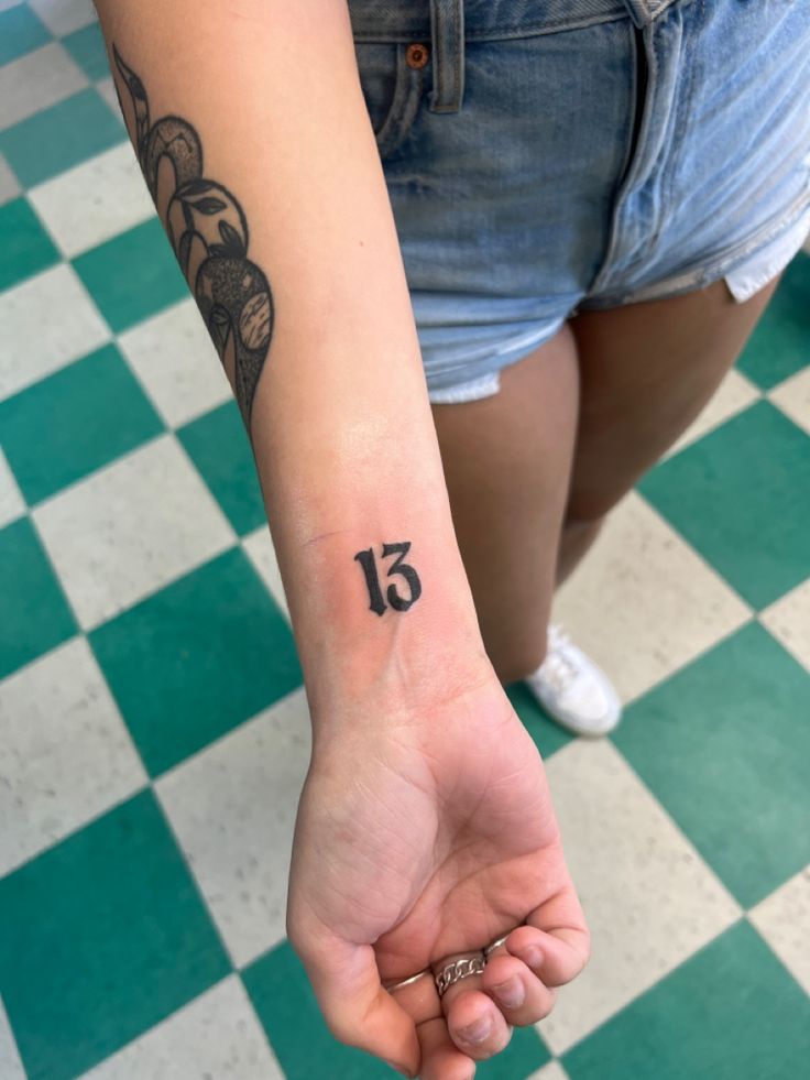 a woman with a tattoo on her arm holding the number fifteen in front of her