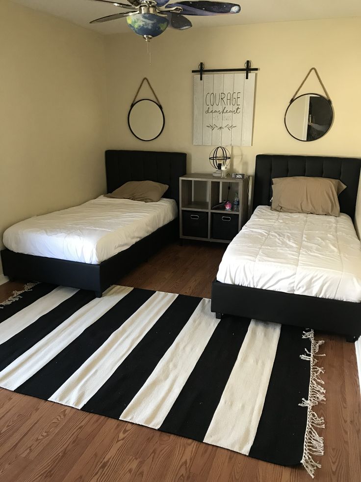 two twin beds in a bedroom with black and white rugs on the hardwood floor