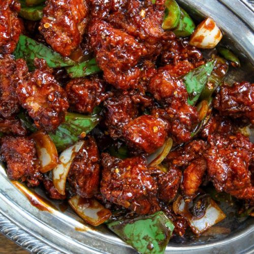 a metal bowl filled with meat and vegetables