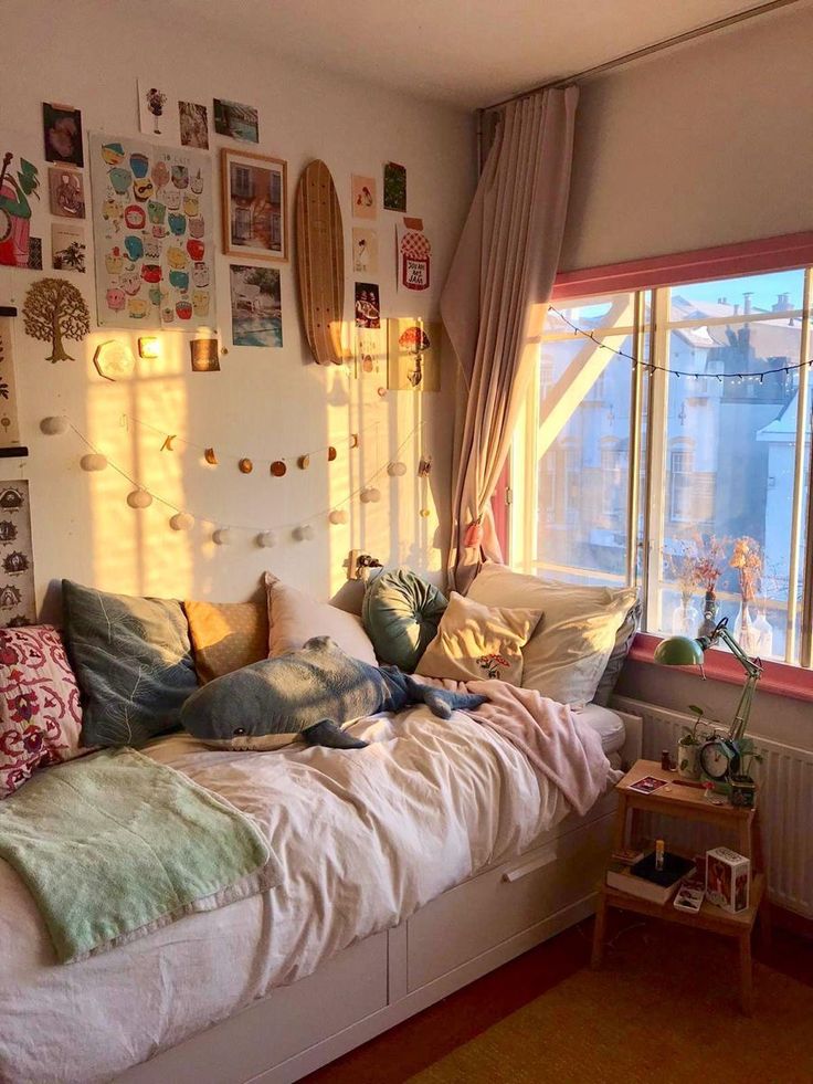 a bed with lots of pillows on top of it next to a window in a room