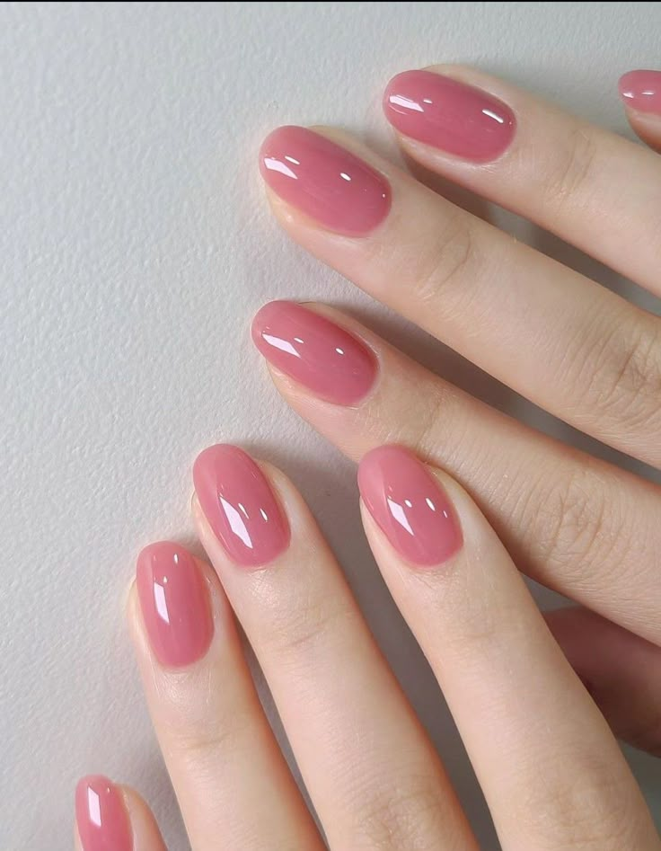 a woman's hand with pink nail polish on her nails, holding onto the tip of her finger