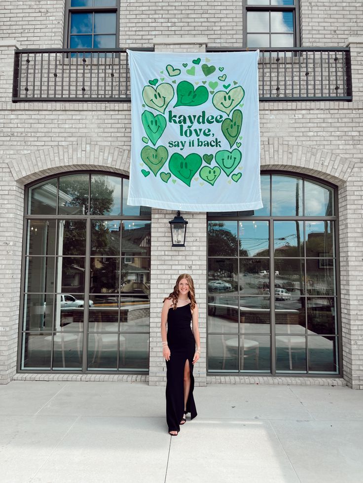 a woman standing in front of a building with a banner hanging from it's side