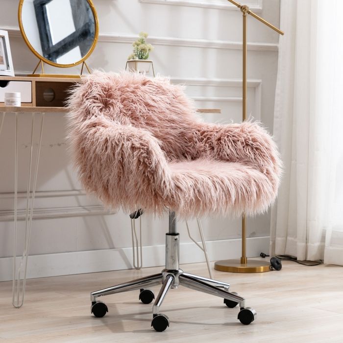 a pink chair sitting on top of a wooden floor next to a mirror and desk