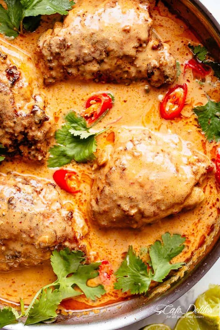 meatballs covered in sauce and garnished with cilantro, limes and red peppers