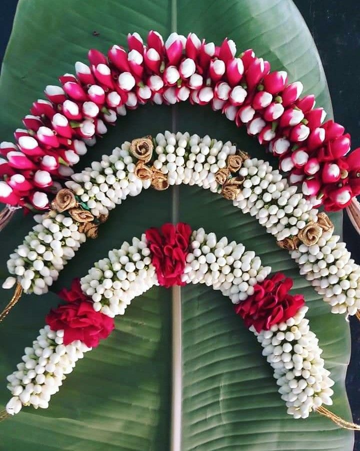 an arrangement of flowers arranged on top of a large green leafy plant with red and white petals