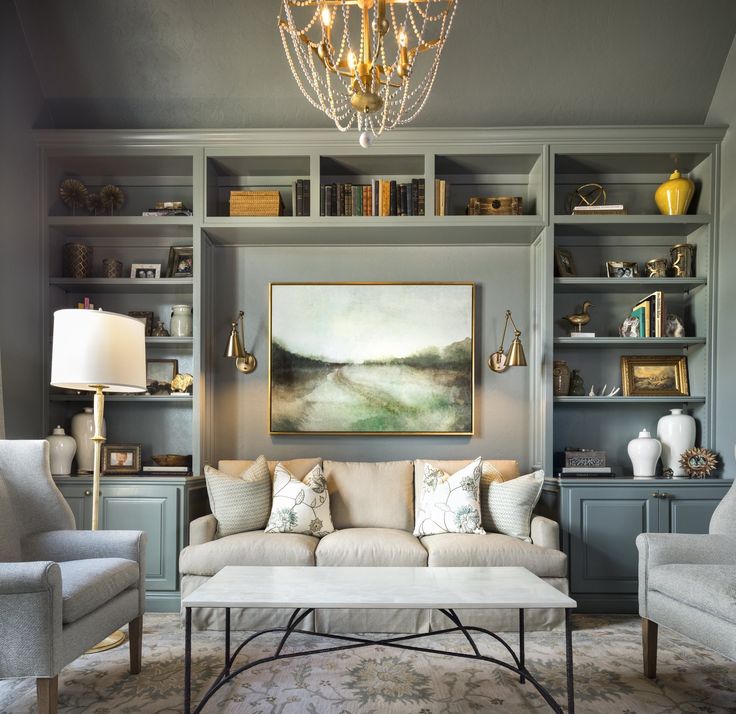 a living room filled with furniture and a chandelier hanging above the couches