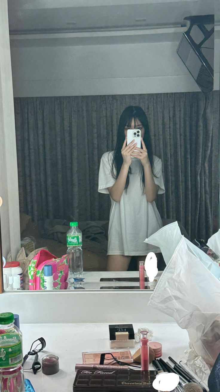 a woman taking a selfie in front of a mirror with makeup on the counter