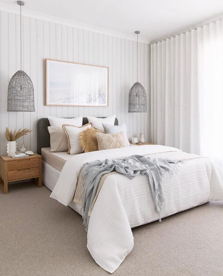 a white bed sitting in a bedroom next to two lamps on either side of the bed