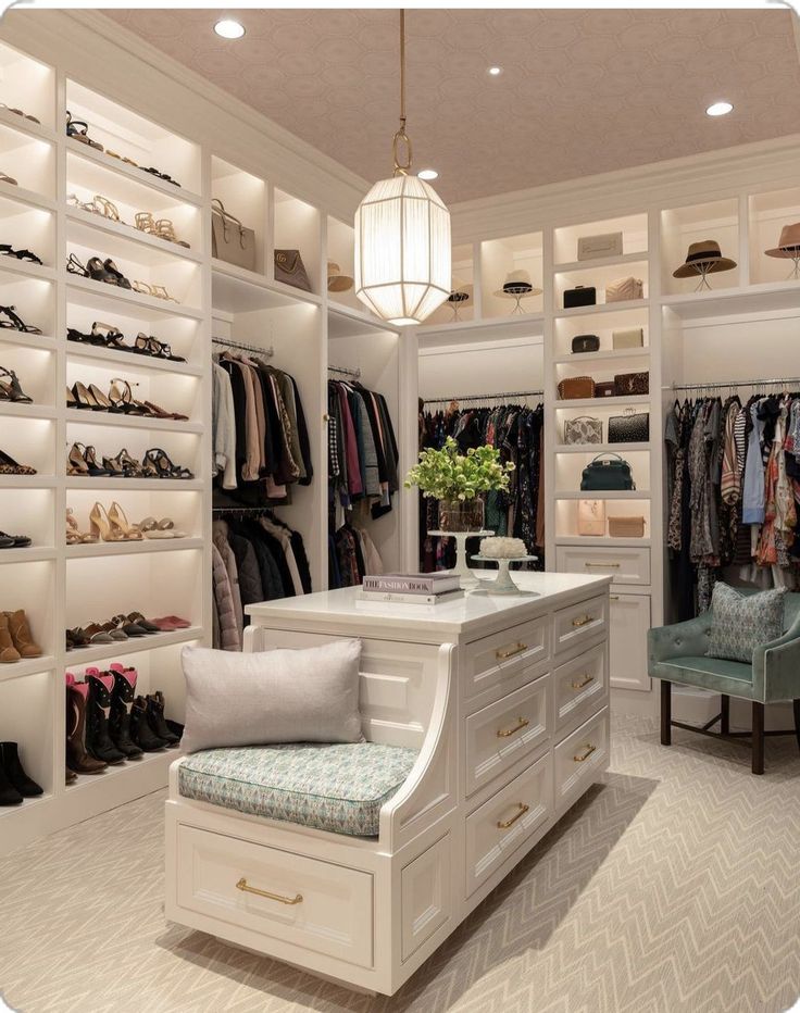 a walk in closet filled with lots of clothes and shoes on shelves next to a blue chair