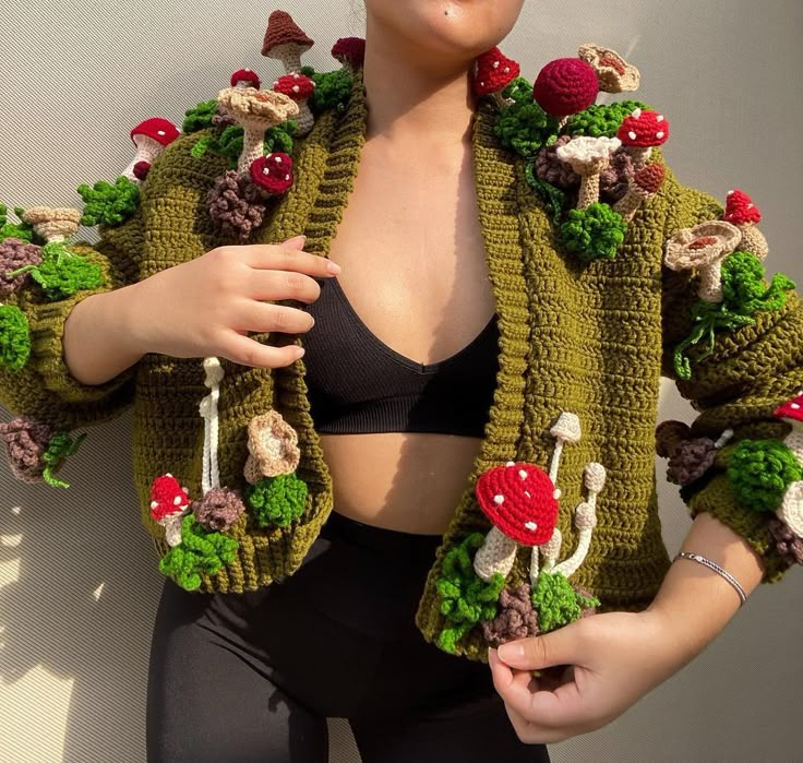 a woman wearing a crop top and jacket with mushrooms on the front, while holding her hands in her pockets