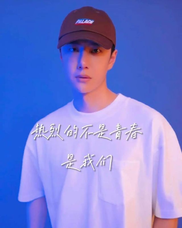 a young man wearing a white shirt and brown hat with chinese writing on it in front of a blue background