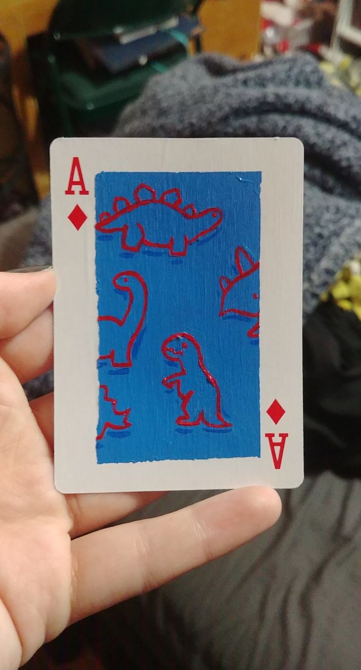 a hand holding up a playing card with red and blue designs on it's sides