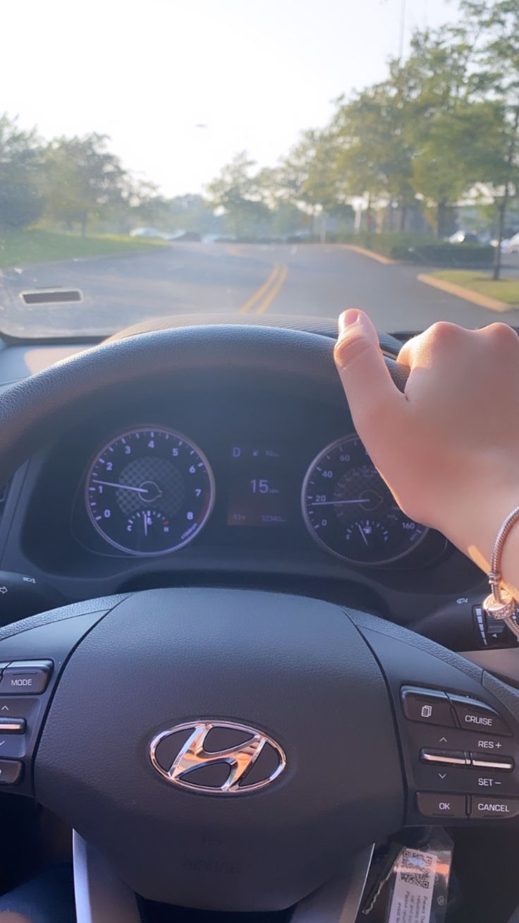 a person driving a car with their hand on the steering wheel and dashboard gauges