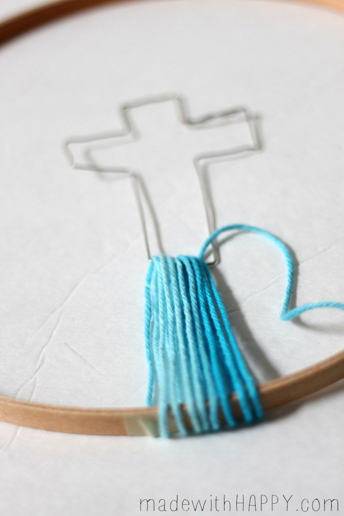 a cross is shown in the middle of a hoop with some yarn on it and a blue thread