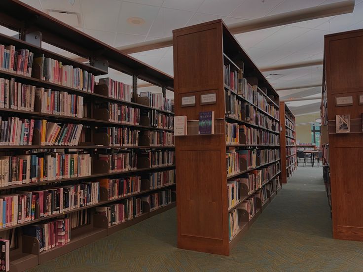 there are many bookshelves in the library with one open door to another room