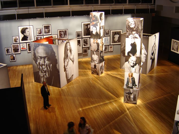 an art gallery with many pictures on the wall and people looking at them from above