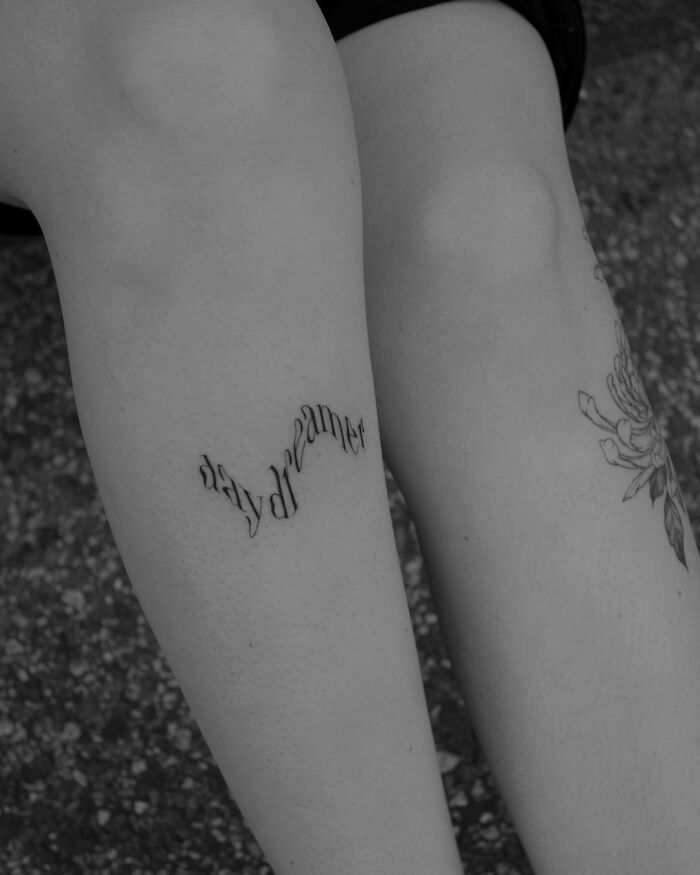 two people with tattoos on their legs and one has the word happiness written in cursive writing