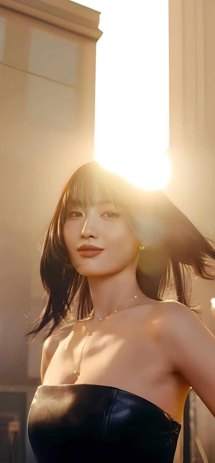 a woman in a black dress posing for the camera with sun shining through her hair