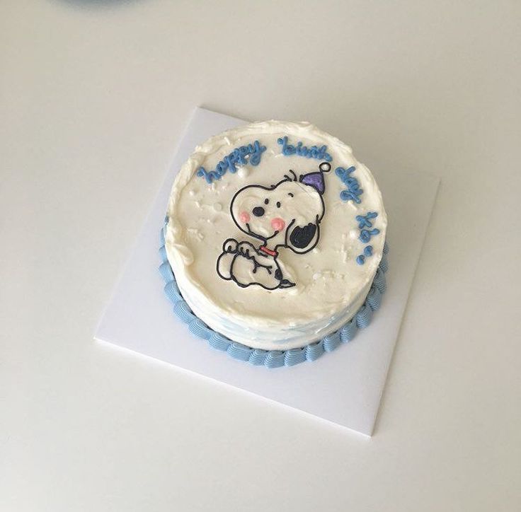 a white frosted cake with a cartoon dog on it's icing sitting on top of a table