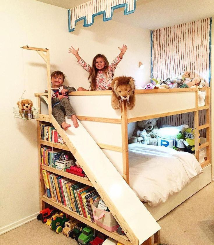 two children are playing on the bunk bed with a slide and bookshelf in front of them