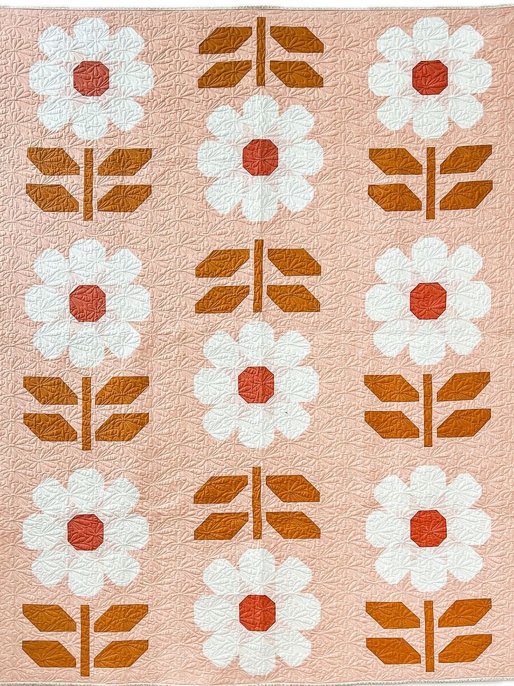 an orange and white quilt with flowers on it