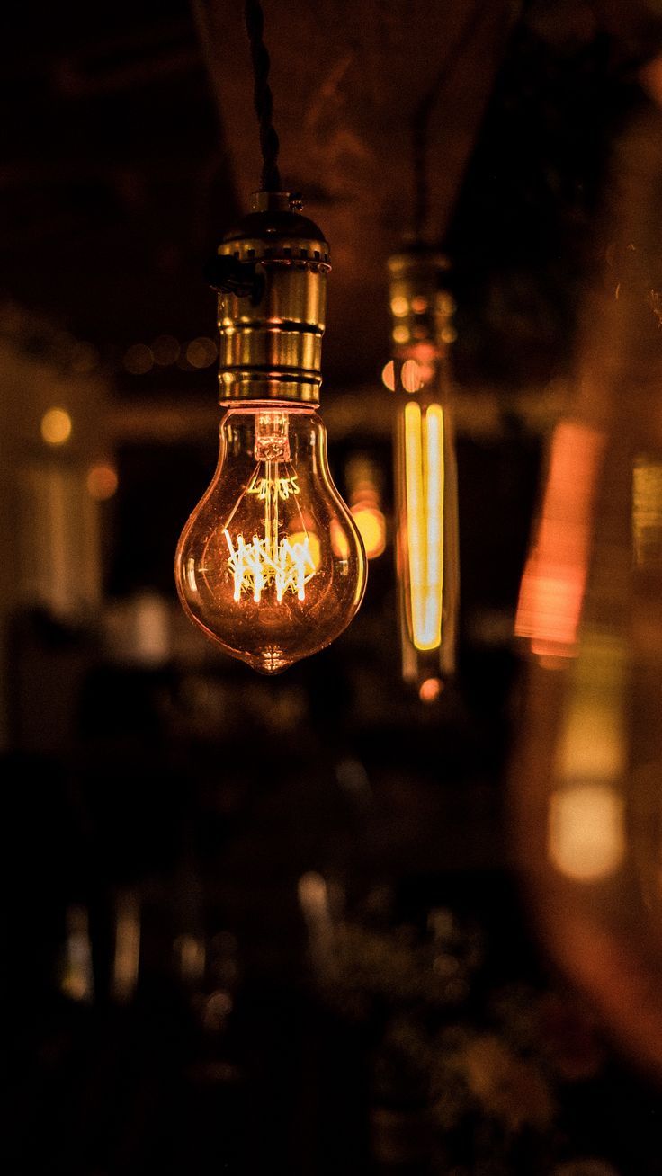 a light bulb hanging from the ceiling in a dark room with other lights on it