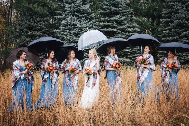 a group of women holding umbrellas standing next to each other in tall grass with trees behind them