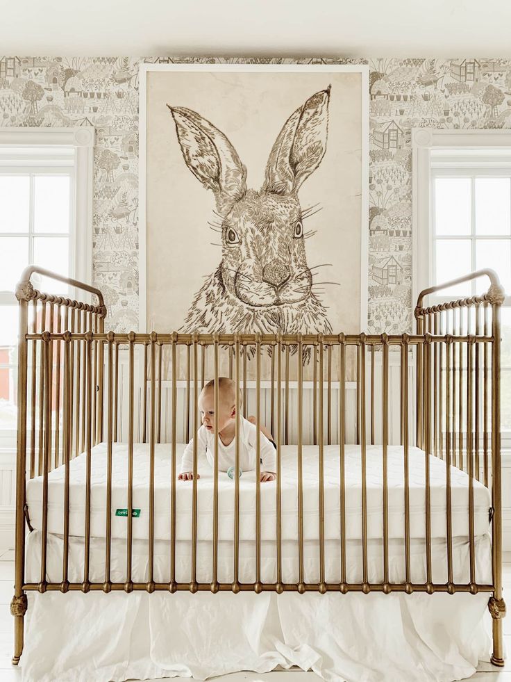 a baby in a crib looking at the wall with a rabbit drawn on it