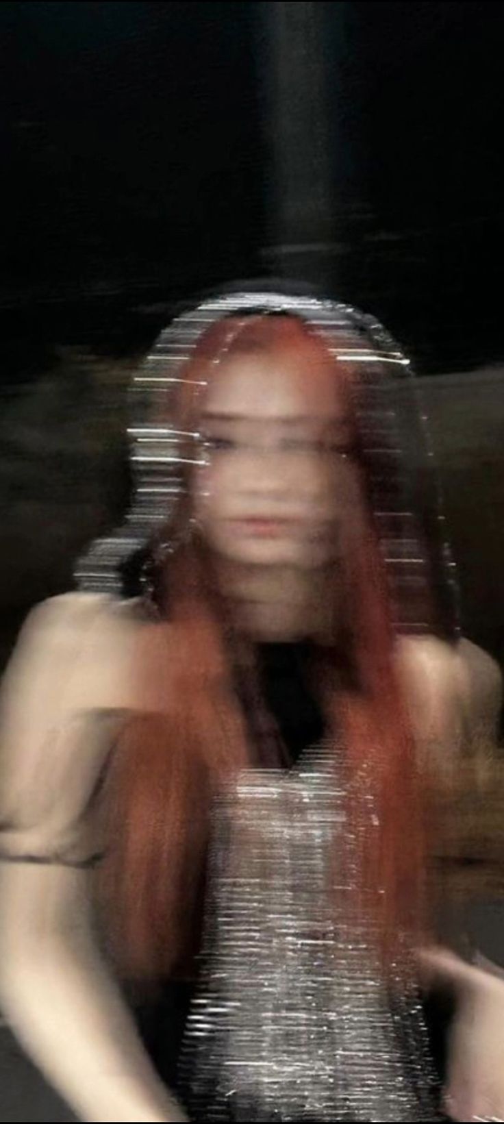 a blurry photo of a woman with long red hair, wearing a silver dress