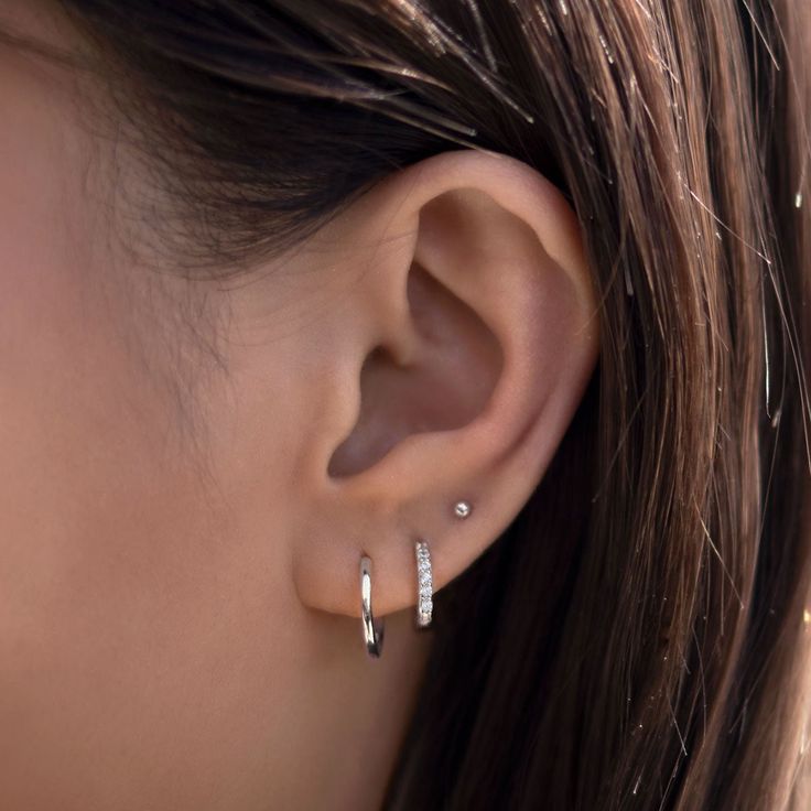 a close up of a person's ear with two small diamond hoops on it