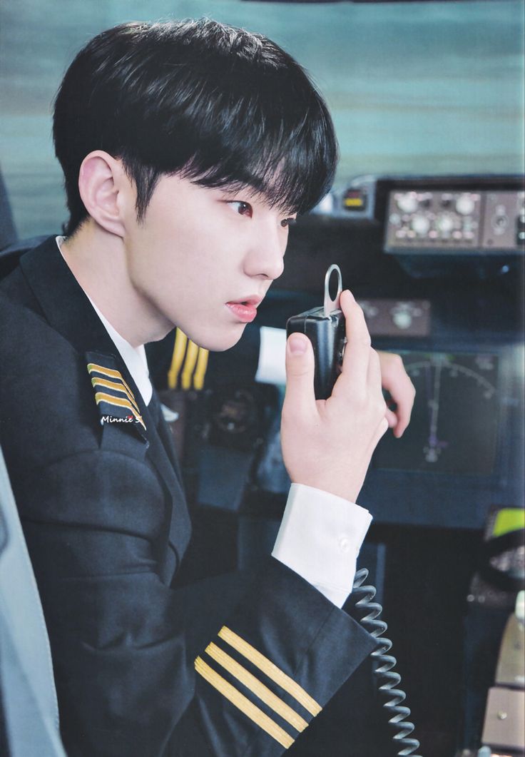 a man in uniform talking on a cell phone while wearing a pilot's uniform