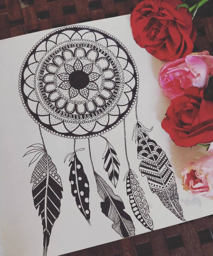 a drawing of a dream catcher next to red roses on a piece of white paper