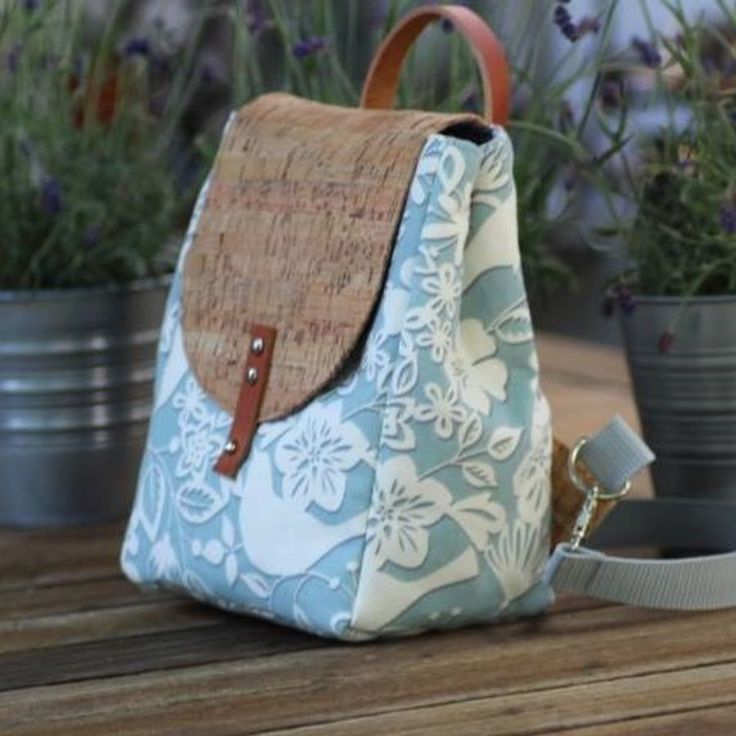 a purse sitting on top of a wooden table next to potted plants and flowers