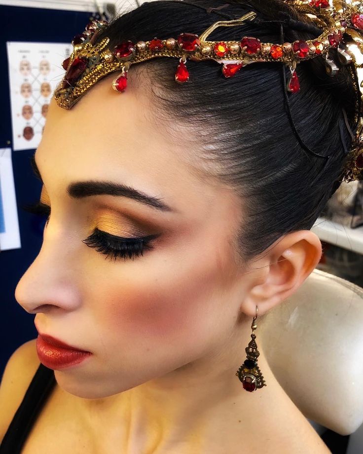 a woman wearing a gold and red headpiece with jewels on it's forehead