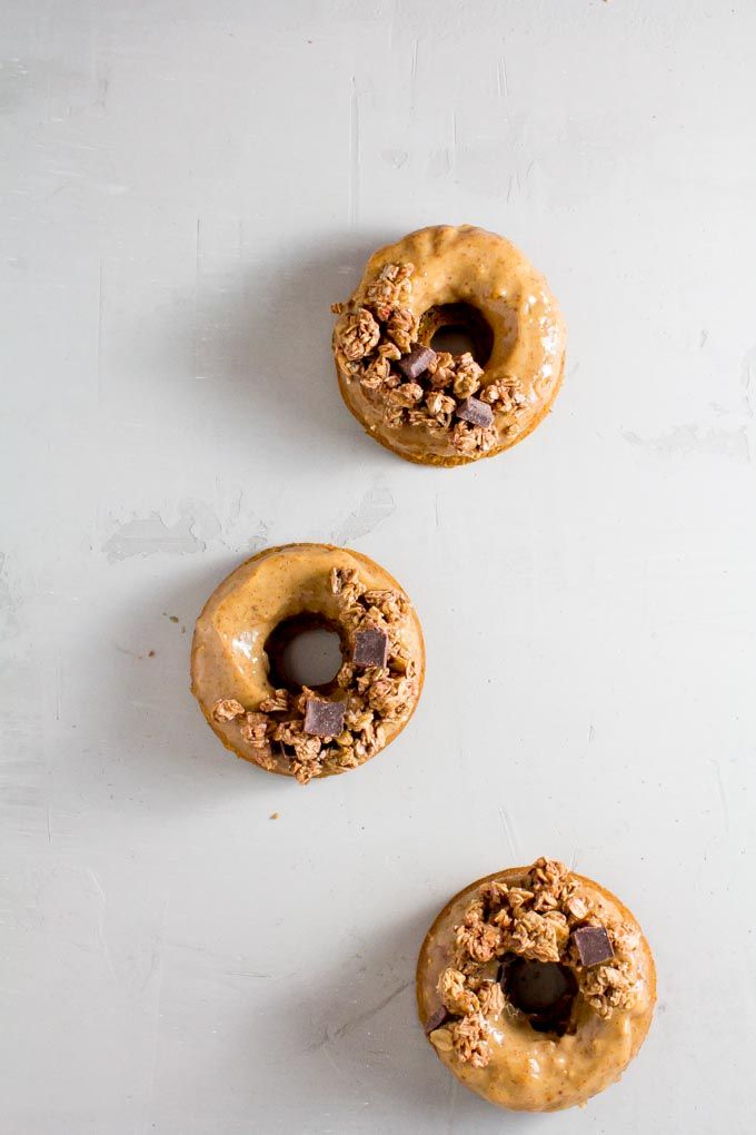 three doughnuts with peanut butter and chocolate chips on top are lined up against a white background