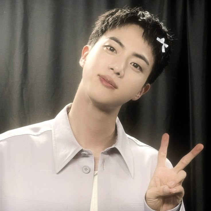 a young man in a white shirt and tie making the peace sign with his fingers