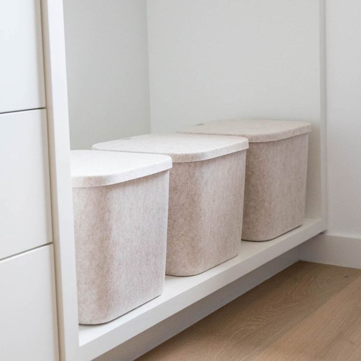 two white bins sitting on top of a shelf next to each other in a room