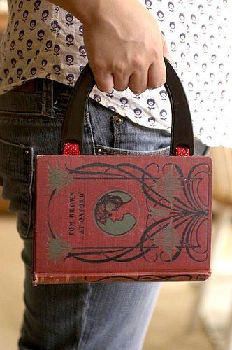 a person holding a red book in their left hand while wearing jeans and a white shirt