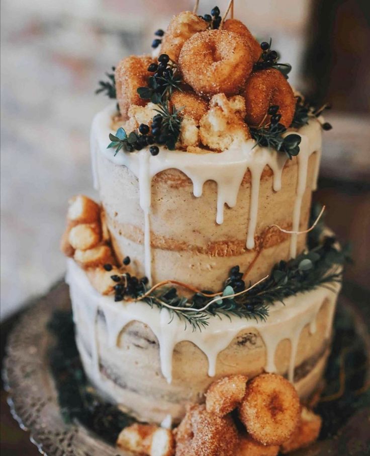 a three tiered cake with donuts on top and icing drizzled over it