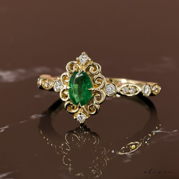 an emerald and diamond ring sitting on top of a table