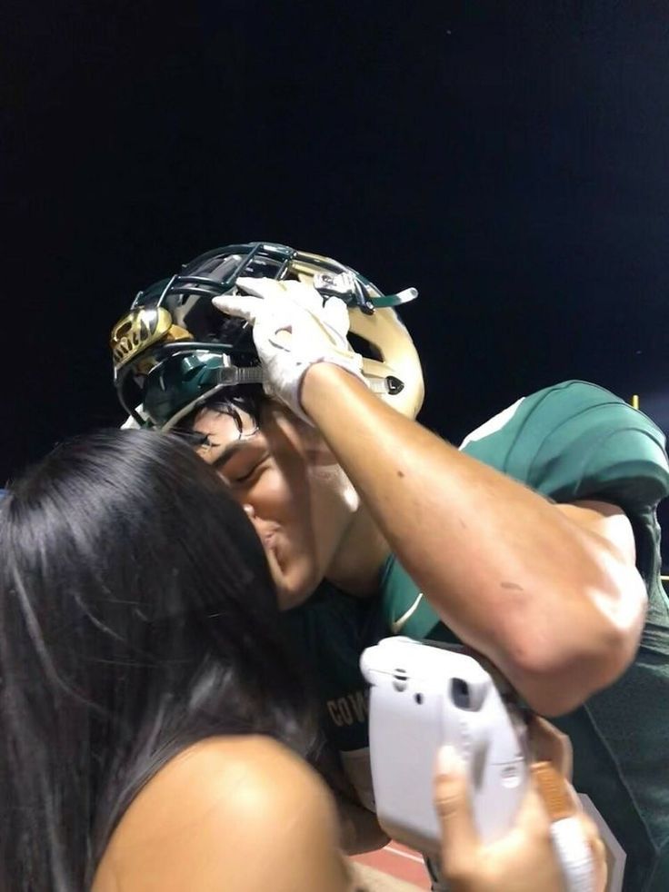 a man and woman embracing each other at a football game