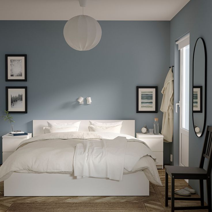 a bedroom with blue walls and white bedding