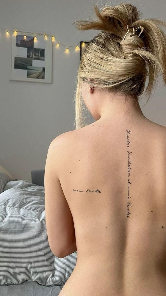 the back of a woman's body with writing on her left shoulder and right arm