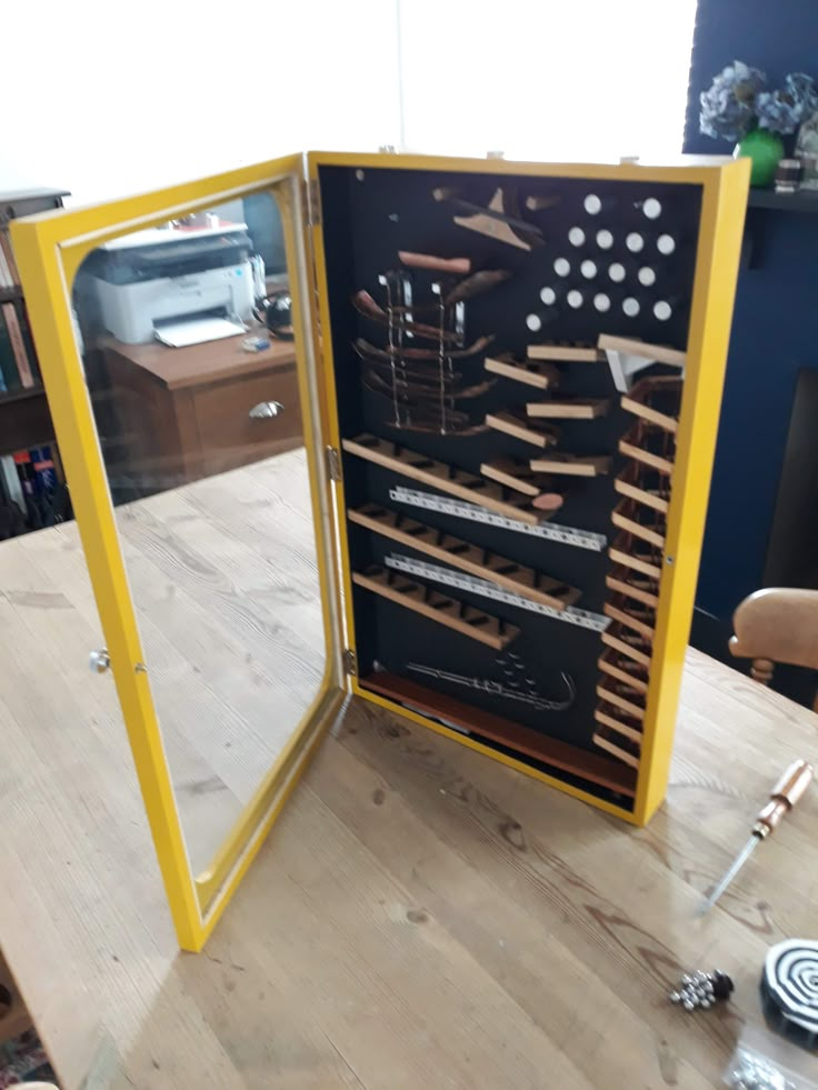 a wooden table topped with lots of tools and a yellow framed case on top of it