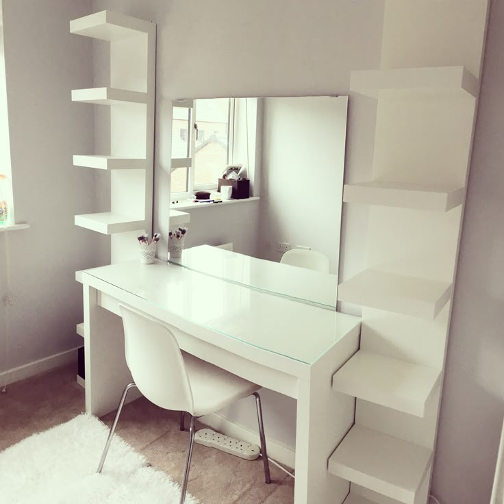 a white desk sitting in front of a mirror on top of a wooden floor next to a window