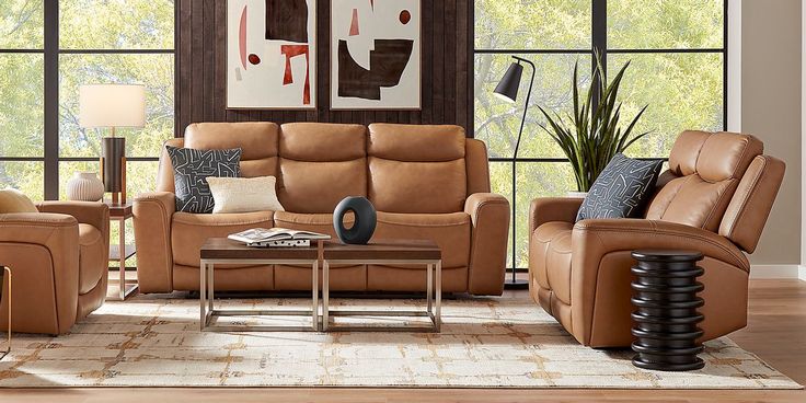 a living room with couches, chairs and tables in front of large windows that look out onto the woods