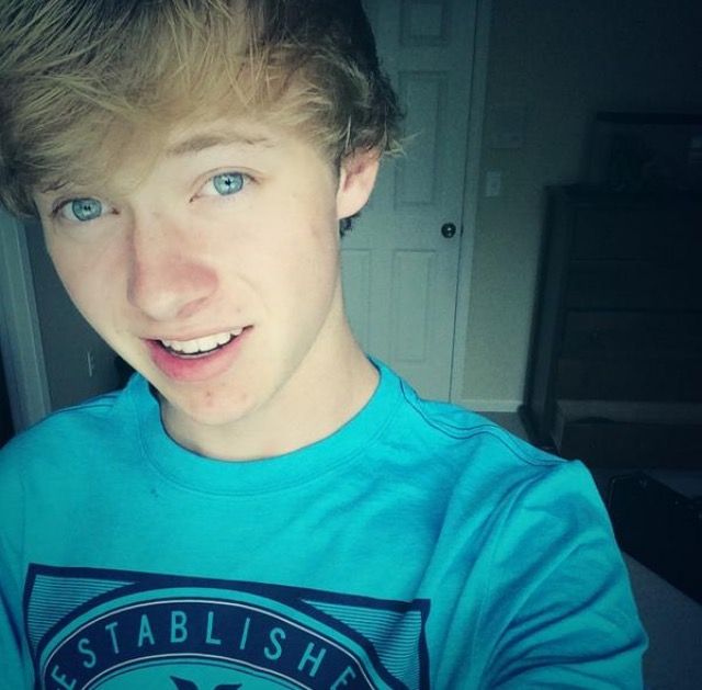 a young man wearing a blue shirt is taking a selfie