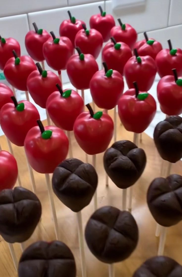 there are many chocolate cake pops with red apples on them in the shape of hearts