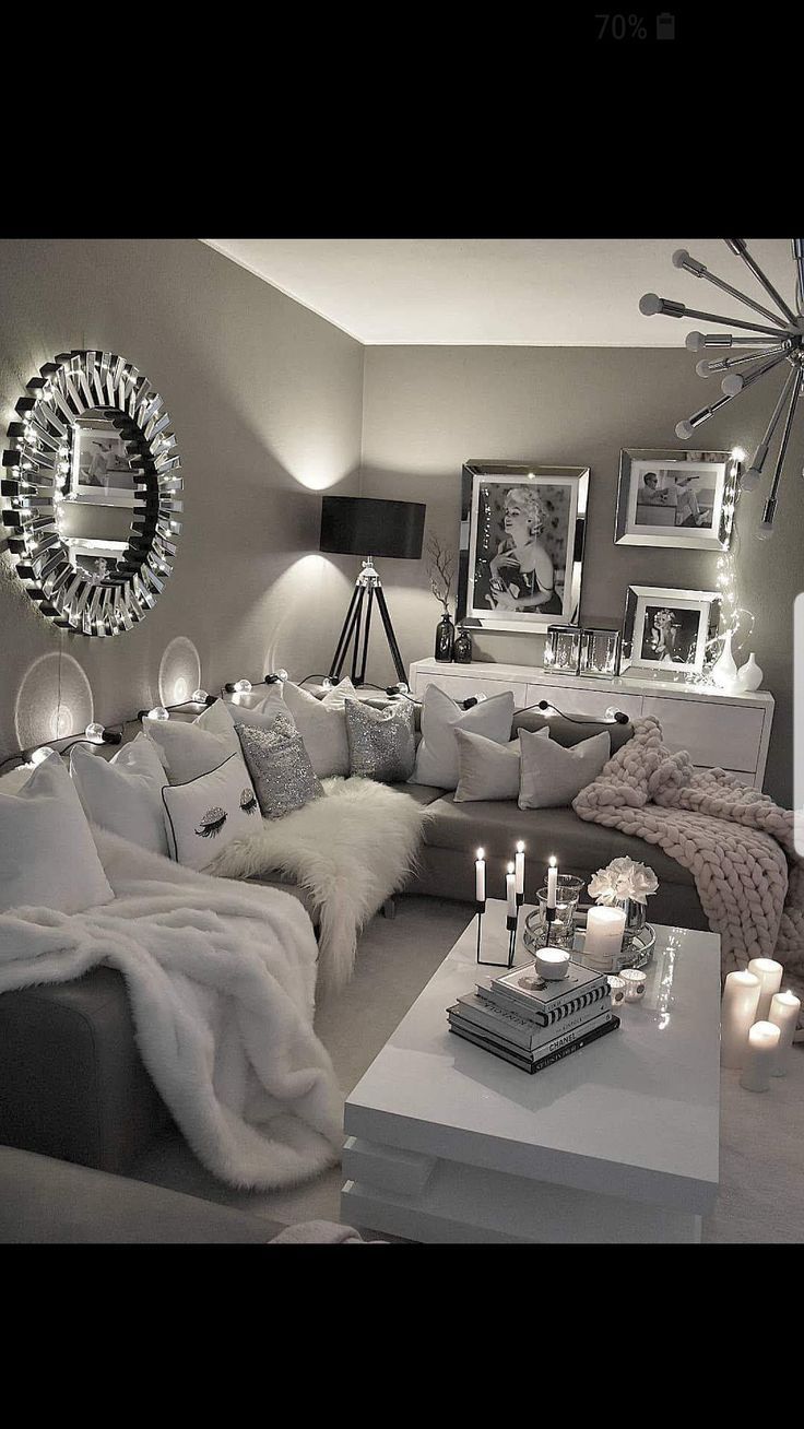 a living room filled with lots of white furniture and candles on top of the coffee table