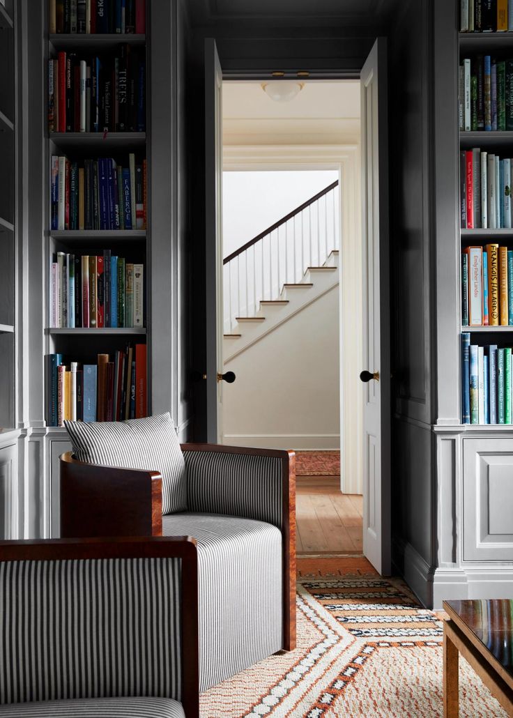 a living room filled with lots of books on top of a book shelf next to a doorway